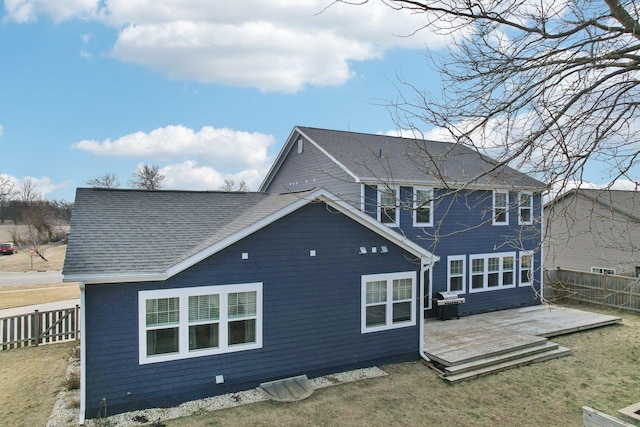 back of property featuring a lawn, roof with shingles, fence, and a wooden deck