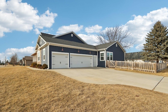 view of side of property featuring concrete driveway, a lawn, an attached garage, and fence