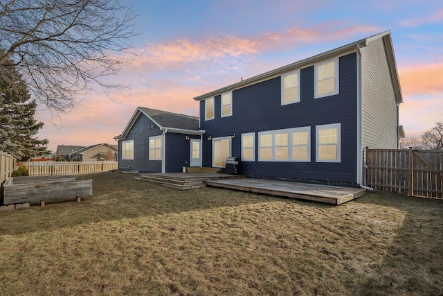 rear view of property with a fenced backyard, a vegetable garden, a lawn, and a wooden deck