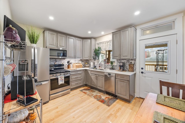 kitchen featuring sink, backsplash, gray cabinets, and stainless steel appliances