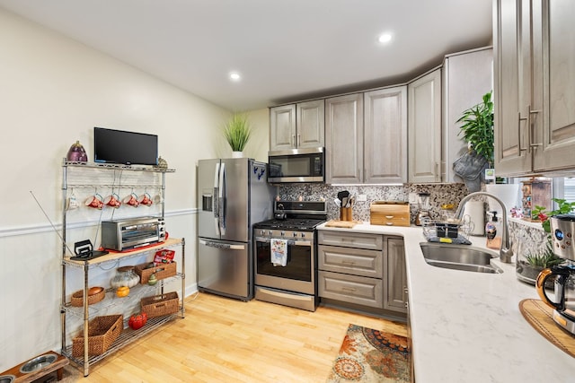 kitchen with sink, gray cabinets, light hardwood / wood-style floors, and appliances with stainless steel finishes