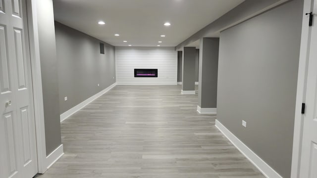 basement with light hardwood / wood-style flooring and a large fireplace