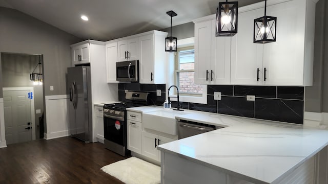 kitchen featuring light stone countertops, appliances with stainless steel finishes, pendant lighting, and white cabinets