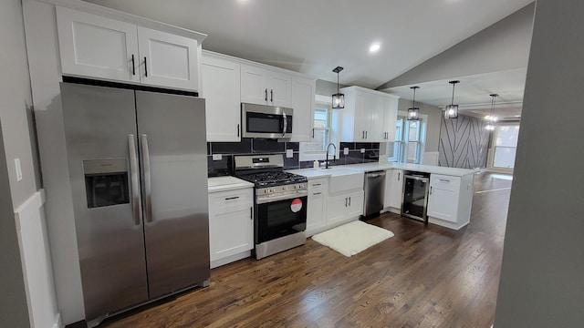 kitchen featuring backsplash, appliances with stainless steel finishes, vaulted ceiling, and white cabinets