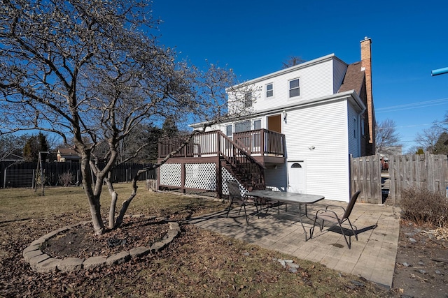 back of property featuring a wooden deck, a yard, and a patio area