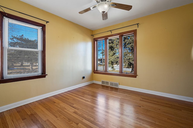 empty room with wood-type flooring, ceiling fan, and plenty of natural light