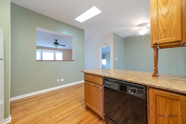 kitchen with light stone counters, ceiling fan, black dishwasher, and light wood-type flooring