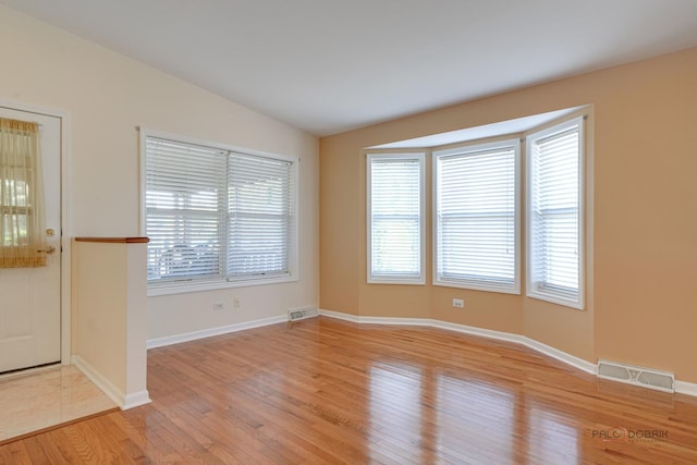 spare room with lofted ceiling, light hardwood / wood-style floors, and plenty of natural light