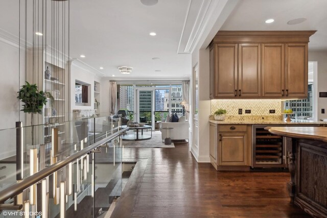 bar featuring wine cooler, backsplash, ornamental molding, light stone counters, and dark wood-type flooring