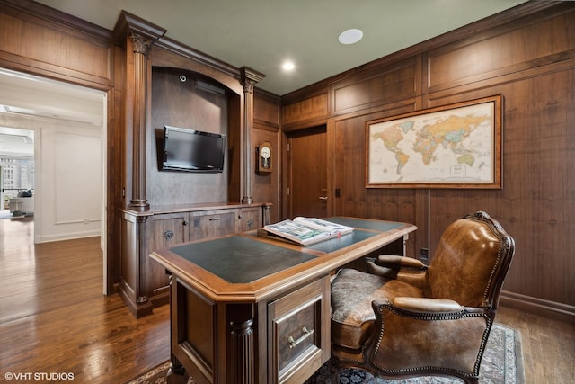 home office with dark hardwood / wood-style flooring and wooden walls