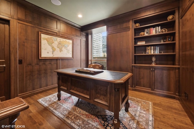 home office featuring dark hardwood / wood-style flooring, wooden walls, and built in shelves
