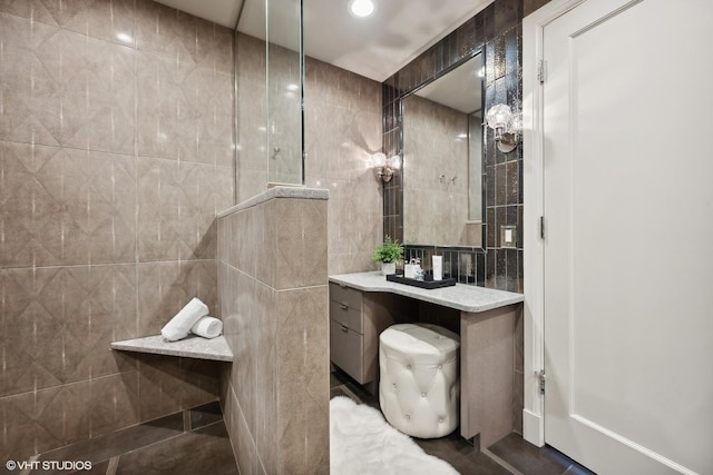 bathroom featuring vanity, toilet, tile walls, and a shower