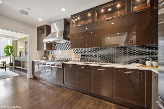 kitchen featuring dark hardwood / wood-style floors, stainless steel gas stovetop, sink, decorative backsplash, and wall chimney range hood