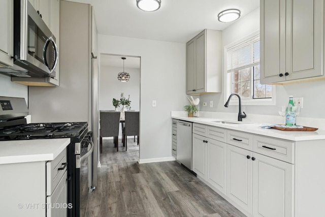 kitchen featuring gray cabinets, appliances with stainless steel finishes, dark hardwood / wood-style floors, decorative light fixtures, and sink