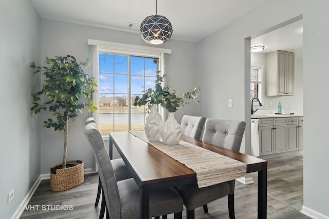 dining space with a healthy amount of sunlight, sink, and light wood-type flooring