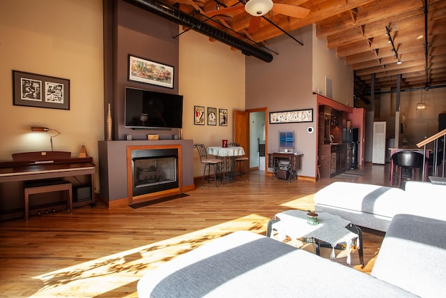 living room featuring hardwood / wood-style flooring, a towering ceiling, wood ceiling, and beam ceiling