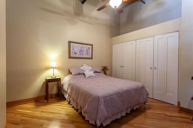 bedroom with a towering ceiling, ceiling fan, and light hardwood / wood-style floors