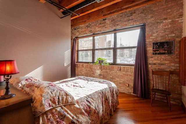 bedroom with hardwood / wood-style floors and brick wall