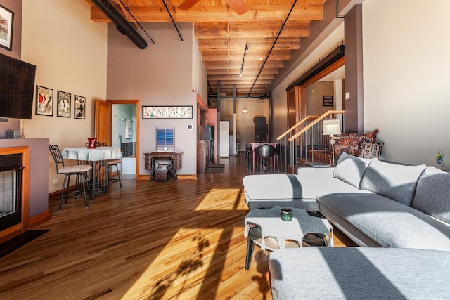 living room featuring wood ceiling, hardwood / wood-style floors, a towering ceiling, and beamed ceiling