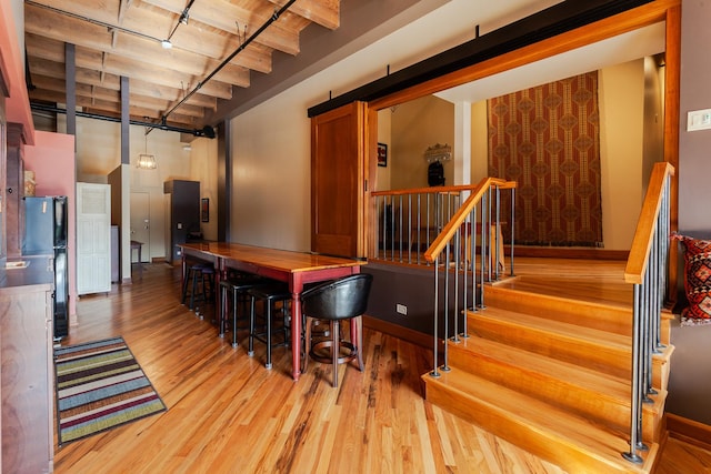 dining area with a towering ceiling, wooden ceiling, beamed ceiling, and light wood-type flooring