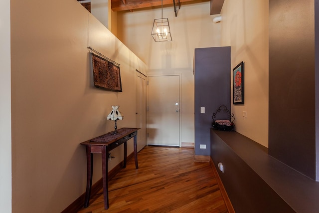 entryway featuring hardwood / wood-style floors, beamed ceiling, and a high ceiling