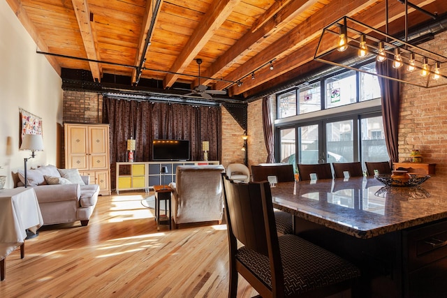 dining area featuring rail lighting, light hardwood / wood-style floors, brick wall, wooden ceiling, and beamed ceiling