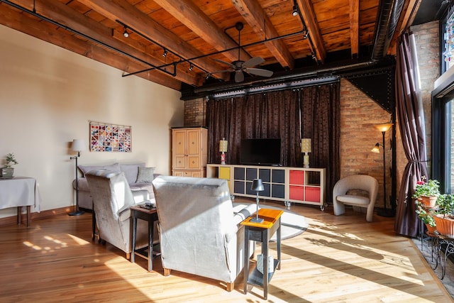 living room with wood ceiling, beam ceiling, track lighting, and brick wall