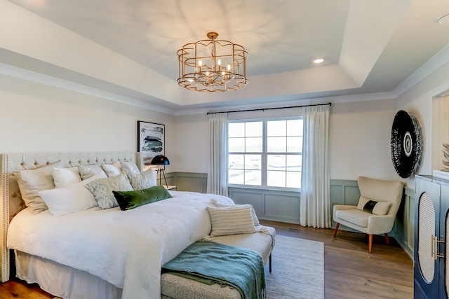 bedroom featuring a tray ceiling, wood-type flooring, and a chandelier