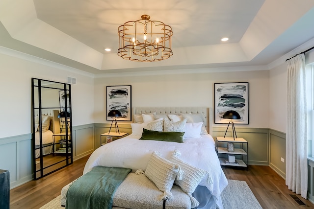 bedroom with a chandelier, a raised ceiling, and hardwood / wood-style floors