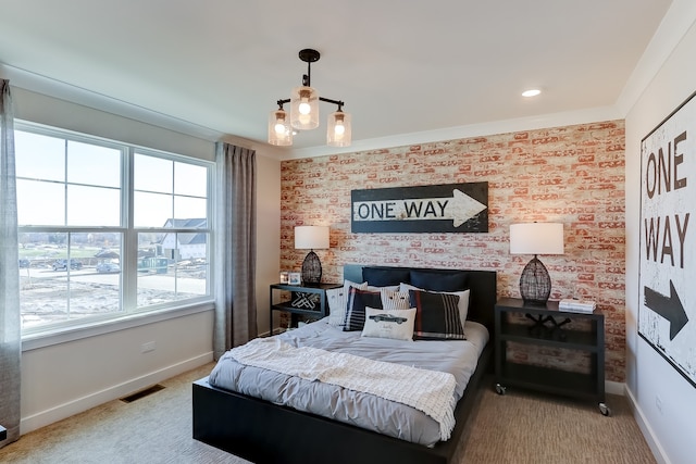 carpeted bedroom with crown molding, brick wall, and a notable chandelier