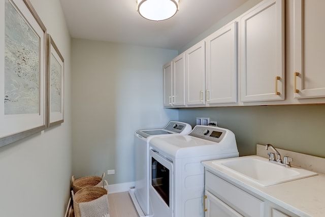 laundry room with sink, washing machine and dryer, and cabinets