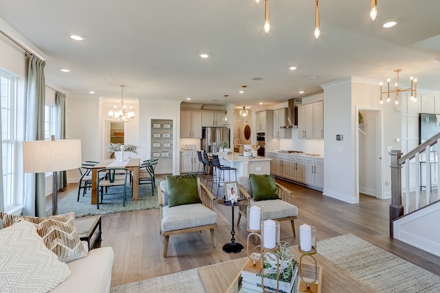 living room featuring ornamental molding, a notable chandelier, and light hardwood / wood-style floors