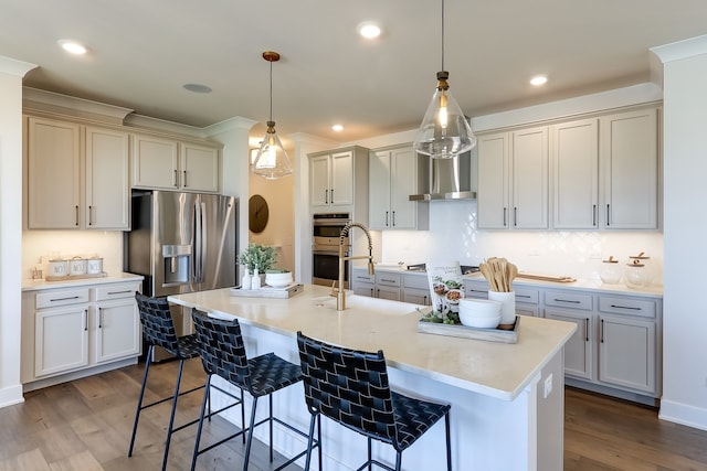 kitchen with a breakfast bar area, dark hardwood / wood-style flooring, a kitchen island with sink, and hanging light fixtures