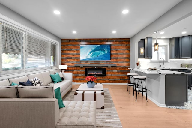 living room featuring sink, light hardwood / wood-style floors, and wood walls