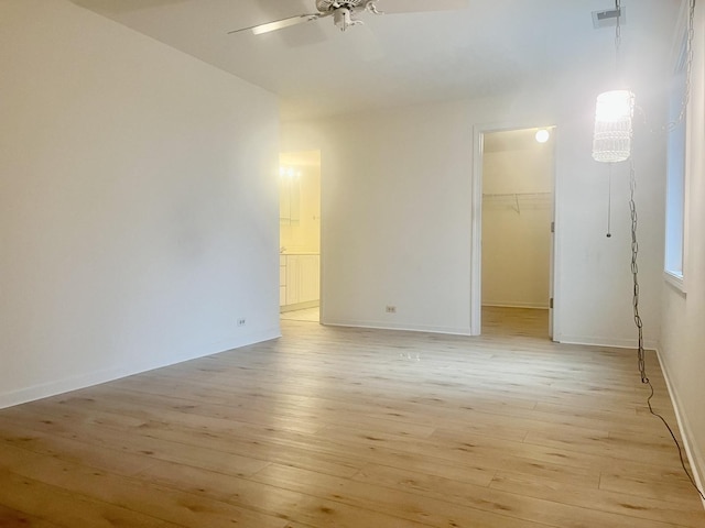 unfurnished room featuring a ceiling fan, light wood-type flooring, visible vents, and baseboards