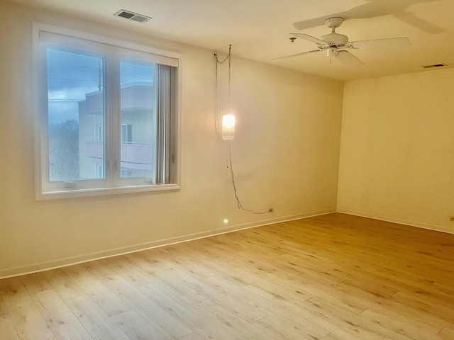 empty room with ceiling fan, wood finished floors, and visible vents