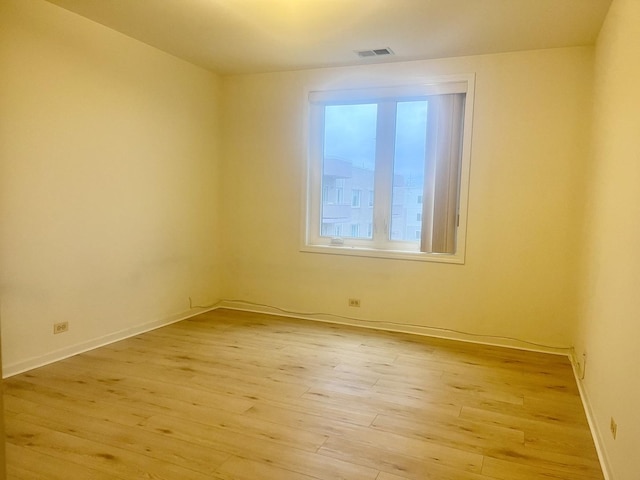 empty room with visible vents, light wood-style flooring, and baseboards