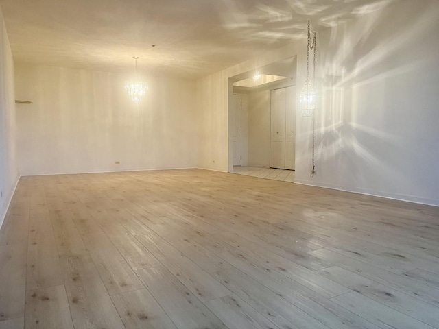 empty room featuring an inviting chandelier and light wood-style flooring