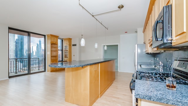 kitchen with pendant lighting, stainless steel gas stove, a kitchen bar, dark stone counters, and a wall of windows