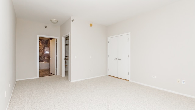 unfurnished bedroom with light carpet, ensuite bath, and a closet