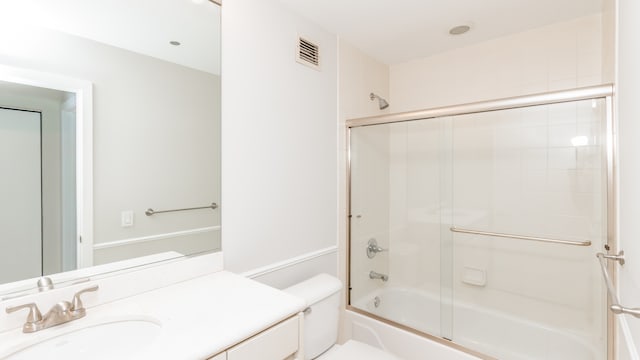 full bathroom with bath / shower combo with glass door, vanity, and toilet