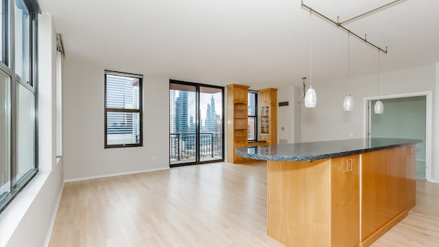 kitchen with pendant lighting, a center island, expansive windows, and light wood-type flooring