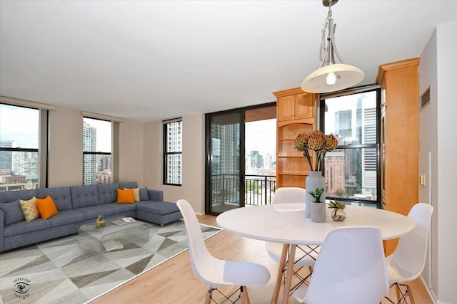 dining area with a wealth of natural light, a wall of windows, and light wood-type flooring