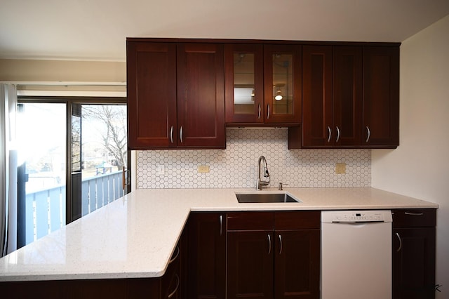 kitchen with sink, tasteful backsplash, dark brown cabinets, white dishwasher, and light stone countertops