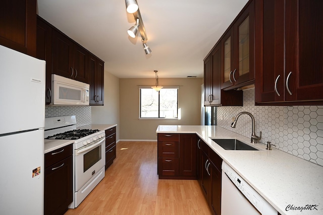 kitchen with decorative light fixtures, rail lighting, sink, light hardwood / wood-style floors, and white appliances