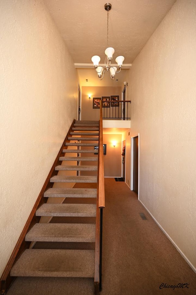 stairway with a chandelier and carpet