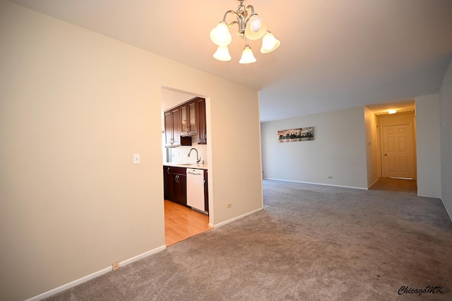 unfurnished living room with sink, light carpet, and a notable chandelier