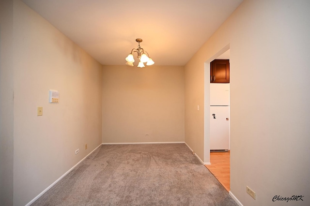 carpeted spare room with an inviting chandelier