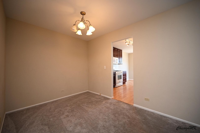 spare room featuring an inviting chandelier and carpet