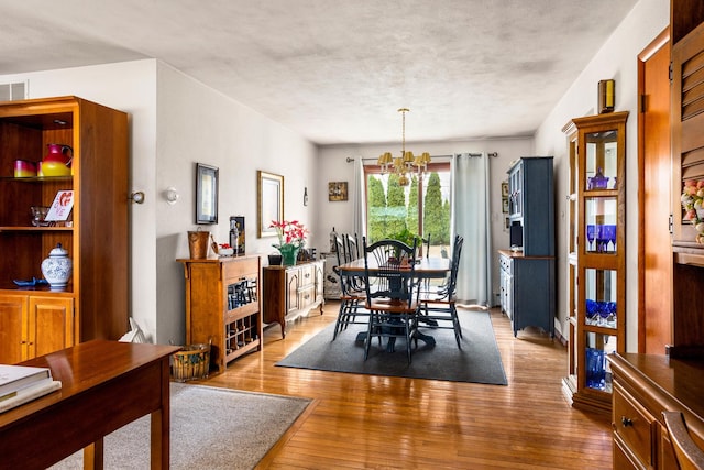 dining space featuring hardwood / wood-style floors, a textured ceiling, and a notable chandelier